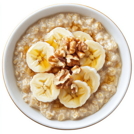 A bowl of warm oatmeal topped with sliced bananas, crushed walnuts, and a drizzle of maple syrup. A comforting and nutritious breakfast option. Isolated on clean white backgroundの素材