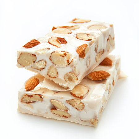 A close-up of a sweet and sticky torrone dessert, an Italian nougat candy, made with honey, sugar, egg whites, and nuts, such as almonds or hazelnuts, served sliced and wrapped in wafer paper, a traditional Christmas treat, isolated on clean white background.の素材