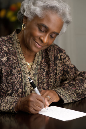 An elderly African-American woman writes thank-you notes to retiring employees. Her tradition of handwritten appreciation letters reflects care, grace, and leadershipの素材