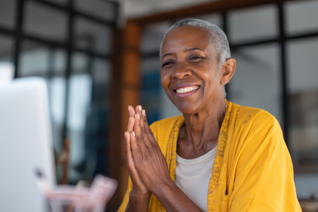 Elderly African-American woman giving closing remarks at a virtual leadership summit, smiling with gratitude and wisdom from years of serviceの素材