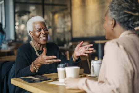 An elderly Black woman gives personal advice to a younger manager during a coffee chat, sharing stories of triumph, burnout, balance, and growing into executive leadershipの素材
