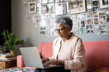 A mature Black woman assembles a digital vision board for a quarterly team goal-setting session, curating imagery and quotes that motivate performance and inspire personal development within the workplaceの素材