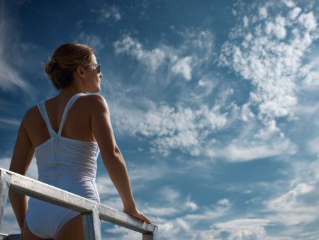 Woman in White Swimsuit on Diving Board Against Cloudy Skyの素材