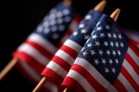 Vibrant image featuring multiple small American flags, showing their iconic red, white, and blue colors. The flags are positioned against a dark, contrasting background, creating a solemn and patriotic mood. Ideal for themes related to patriotism, national holidays, and American culture, this image captures a symbolic representation of the United States.の素材