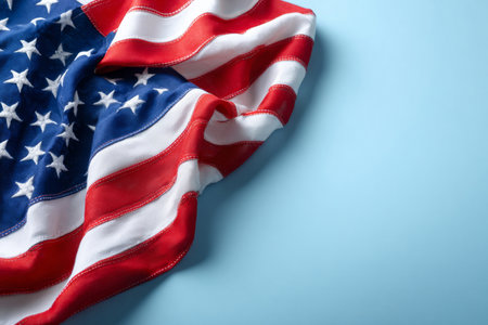 The United States flag set to the left against a light blue backdrop with room for messagingの素材
