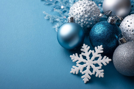 A refined set of ornaments and a snowflake decorates a cool blue background, creating a classy seasonal mood.の素材