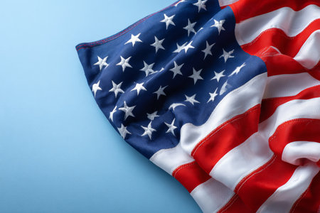 American flag arranged in the upper left against a light blue surface designed for US holiday messagingの素材