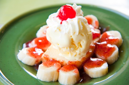 one scoop of vanilla ice-cream topping with banana, cream, red jelly and chocolateの写真素材