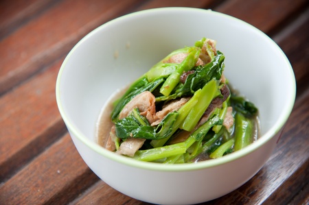 Stir-fried mix colorful vegetables and herb in white round bowl on wood pattern backgroundの写真素材