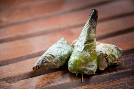 Delicious Thailand dessert, sticky rice toast with taro and banana leaf on wood backgroundの写真素材
