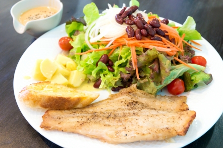 Fish steak with salad, dipping sauce and garlic breadの写真素材