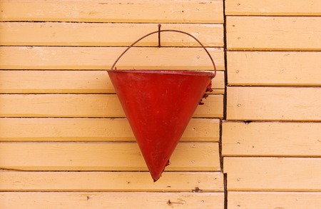 triangular red fire bucket hanging on the pink wallの写真素材