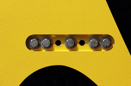 cap screws and holes in the yellow-black background - on the construction equipment compactorの写真素材