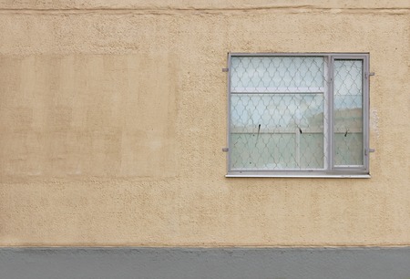 one gray window with a safety guard on the first floor of a modern building on a beige background Plastered walls.の写真素材