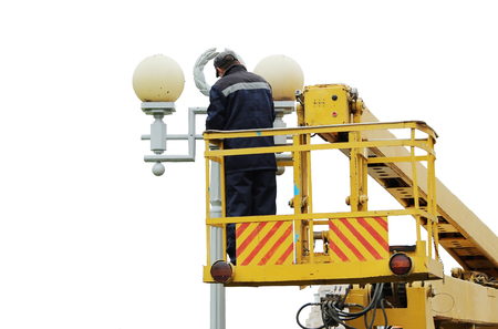 Isolated Electrical worker repairing the wires on the pole with the help of the lift carの写真素材