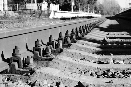 black and white photo bolts that secure the rails to the sleepers on the railway directionの写真素材