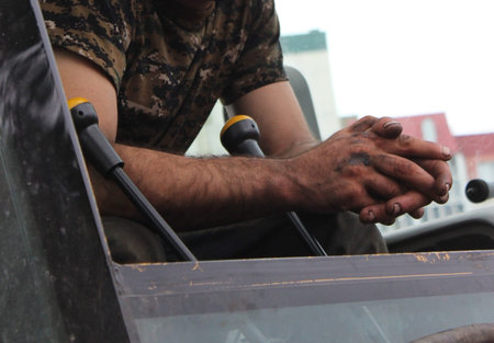 handles and working hands of worker in excavator soiled in the engine oil