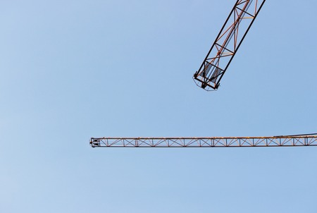 two jib cranes against a cloudless blue skyの写真素材