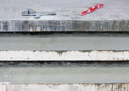 Tools: Two trowel, level on the steps and wooden formwork filled with concrete mixの写真素材