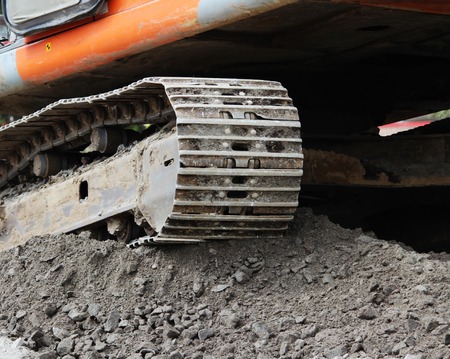 heavy orange crawler excavator is standing on the construction site of repair and expansion of the roadの写真素材