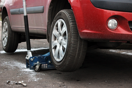 installation of passenger car wheel and replacement on winter tire in winter cloudy day outdoorsの写真素材