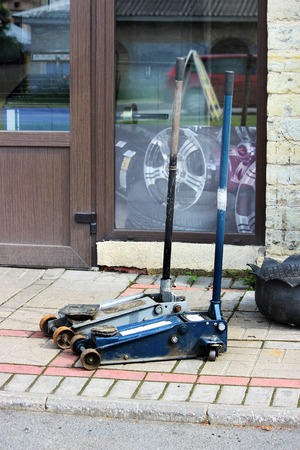 two working jack for repairing cars on the background of paving slabs near the service stationの写真素材
