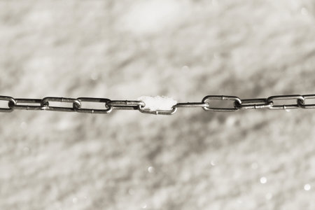 black and white photo galvanized chain enclosing the parking lot for the cars on the background of...