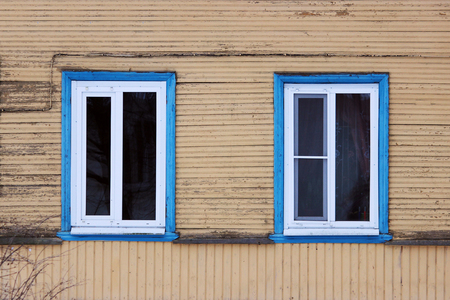 Two windows in the blue framed in a wooden house, painted beige paint.の写真素材