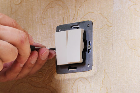 Worker man electrician is repairing damaged switch in the apartment, installation of new closeup.の写真素材