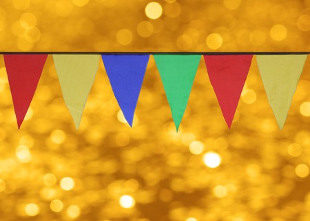 Multi Colored Triangular Flags Hanging against the backdrop of gold bokehの写真素材