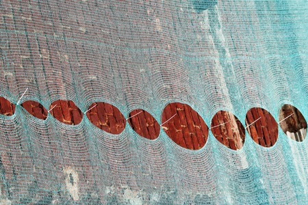 Under construction building wrapped with green net and cable ties for debris safetyの写真素材