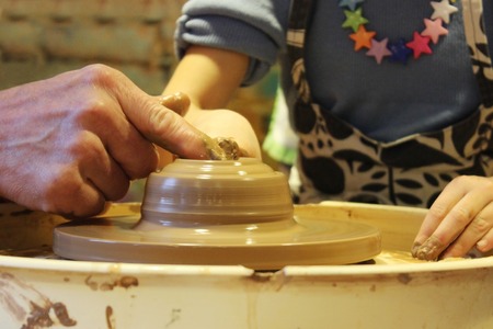 experienced master potter teaches the art of making pots of clay on the potter's wheel.の写真素材