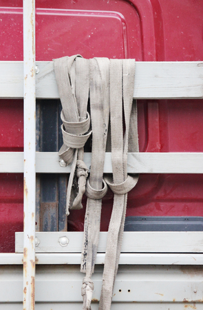 torn gray nylon slings hanging on board the truckの写真素材