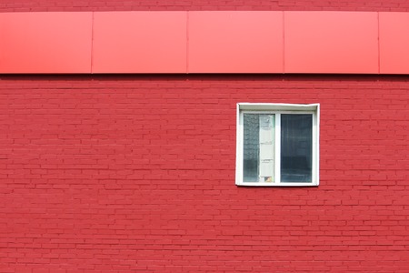 The texture of bright red brick wall with canopy and white window on a sunny dayの写真素材