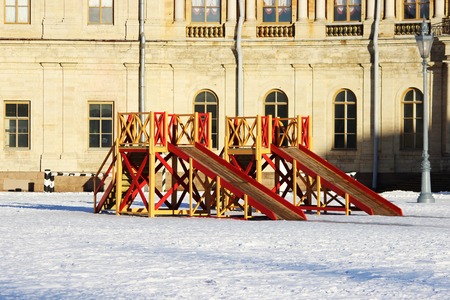 Two wooden red and yellow children's slides built on the square in front of the palace in winterの写真素材