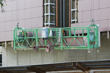 work with green front two suspended cradle without workers on a newly built high-rise buildingの写真素材