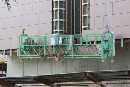 work with green front two suspended cradle without workers on a newly built high-rise buildingの写真素材