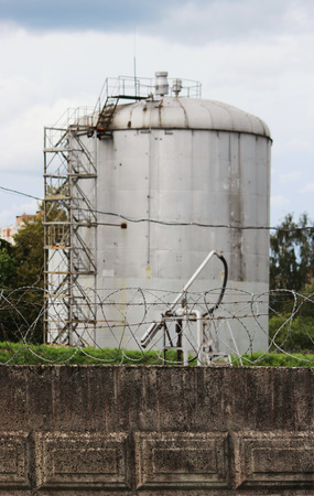 metal tower with flammable fuel in the territory of a fence with barbed wire.の写真素材