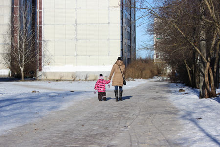 woman with little daughter walking along the road near the houseの写真素材