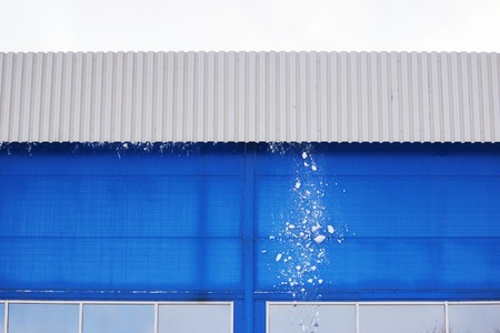Worker cleans snow from the roof of a large sports complexの写真素材