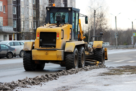 tractor cleans the road in the city of dirty snow.の写真素材