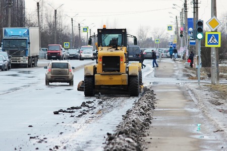 tractor cleans the road in the city of dirty snow.の写真素材