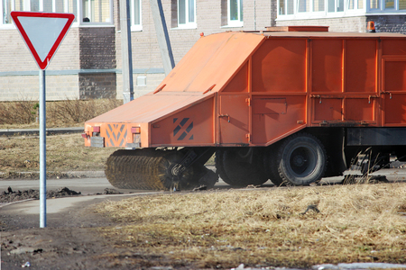 Orange urban sweeper cleans road from dirt with a round brush in the springの写真素材