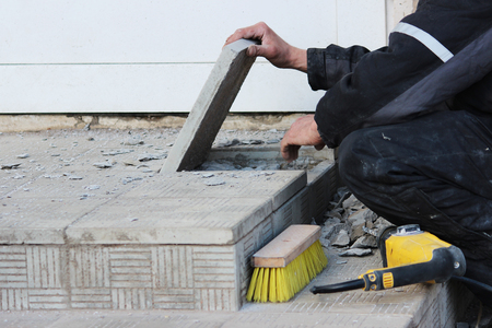 professional construction worker laying stone tiles on the porch at the entrance to the store.の写真素材
