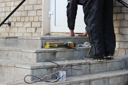 professional construction worker laying stone tiles on the porch at the entrance to the store.の写真素材