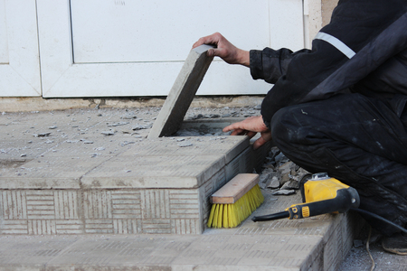 professional construction worker laying stone tiles on the porch at the entrance to the store.の写真素材