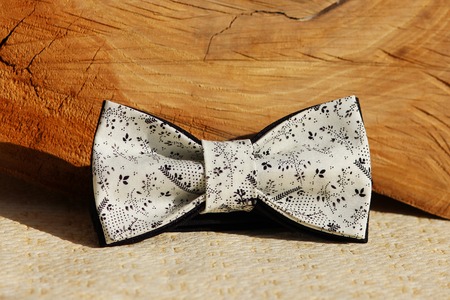 Composition: Extravagant beige with a black fine pattern of a bow tie, a wooden cut on a beige background.の写真素材
