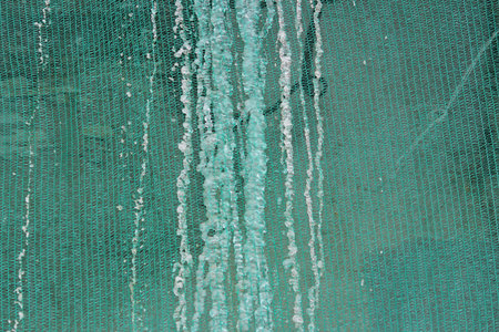 Restoration of the building and a protective green building mesh with frozen water that drained from...