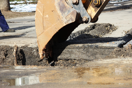 opening the road surface when eliminating accidents under the ground. Using of a tractor with a special attachment and an excavator with a bucket.の写真素材