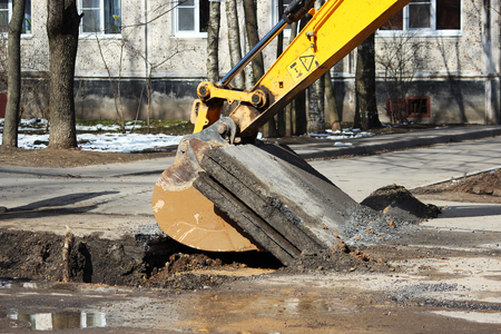 opening the road surface when eliminating accidents under the ground. Using of a tractor with a special attachment and an excavator with a bucket.の写真素材